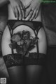 A black and white photo of a woman in lingerie with roses on her butt.